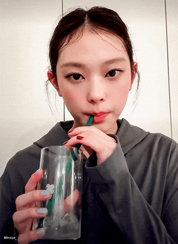 a woman drinking through a straw from a glass