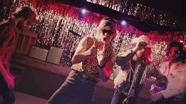 a man in a leopard print shirt is giving a thumbs up to the camera