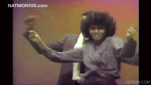 a woman is dancing in front of a screen that says nat morris.com on it