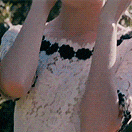 a woman in a white lace dress is covering her face with her hands