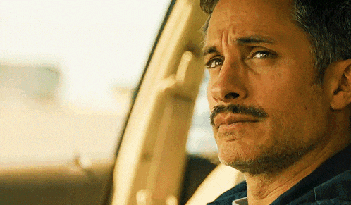 a man with a mustache is sitting in a car