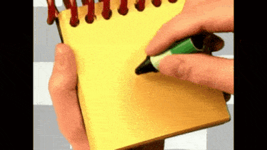 a person is writing on a yellow spiral notebook with a green marker