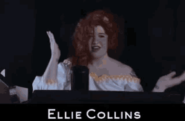 a woman in a red wig is sitting in front of a computer screen .