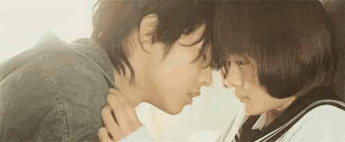 a man and a woman are kissing in front of each other .