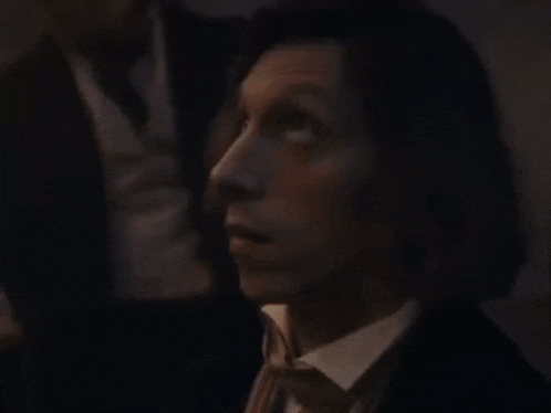 a man in a suit and tie is looking up in the dark