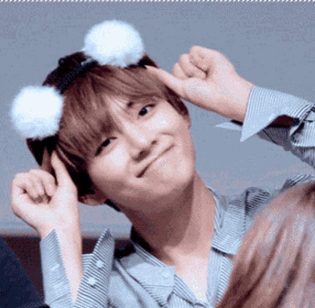 a young man wearing a headband with white pom poms on his head