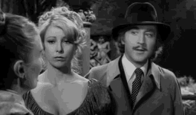 a black and white photo of a man and two women standing next to each other .