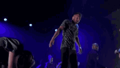 a group of people are dancing on a stage in front of purple lights