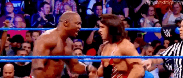 a man and a woman are wrestling in a wrestling ring while a referee watches .