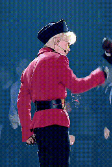 a man in a red jacket and black hat is singing into a microphone ..