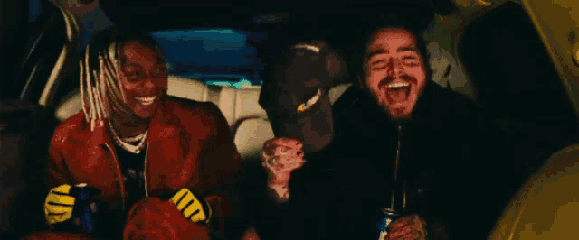two men are sitting in the back seat of a car and one has a can of dr pepper in his hand
