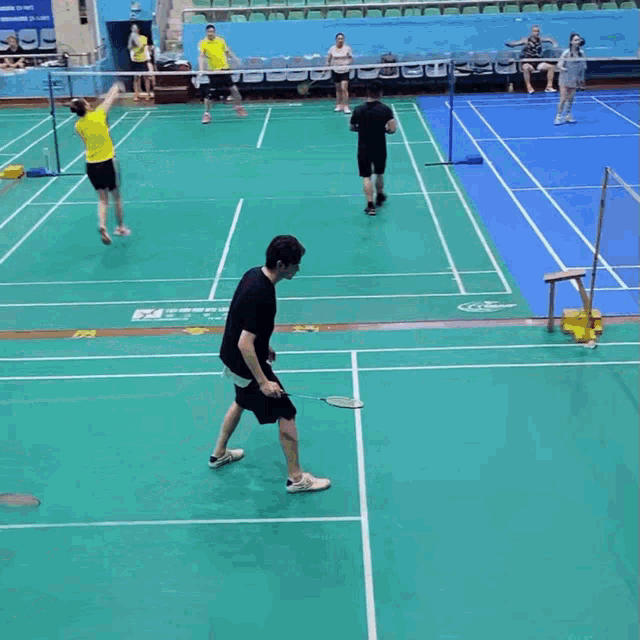 a group of people are playing badminton in a gym