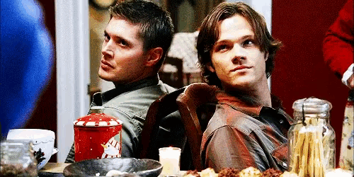 two men are sitting at a table with a candy cane in the background