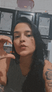 a woman with a tattoo on her arm holds her hand up to her face