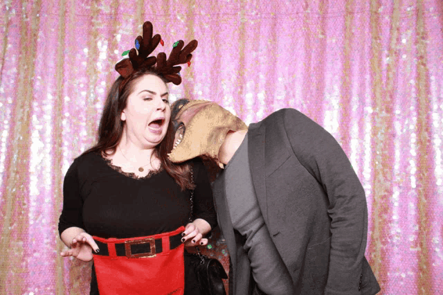 a woman wearing reindeer antlers and a man wearing a shark mask