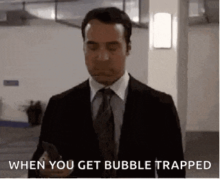 a man in a suit and tie is holding a cell phone and saying `` when you get bubble trapped '' .