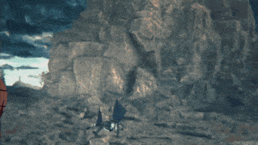 a person standing in front of a cliff with rocks in the background