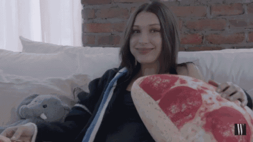a woman sitting on a couch holding a pizza pillow
