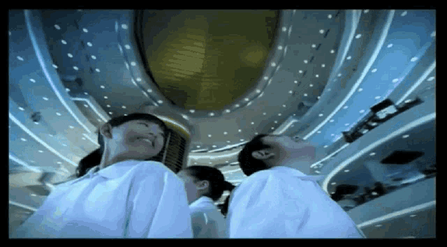 a man and a woman are looking up at the ceiling of a large building