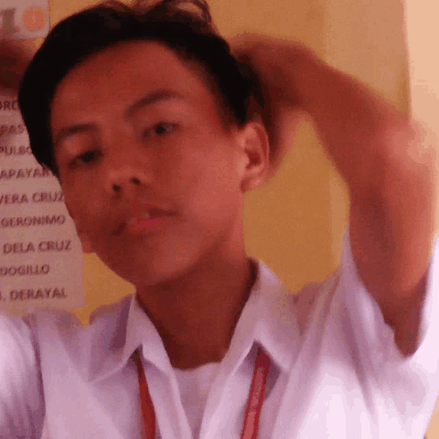 a young man adjusts his hair in front of a sign which says 10