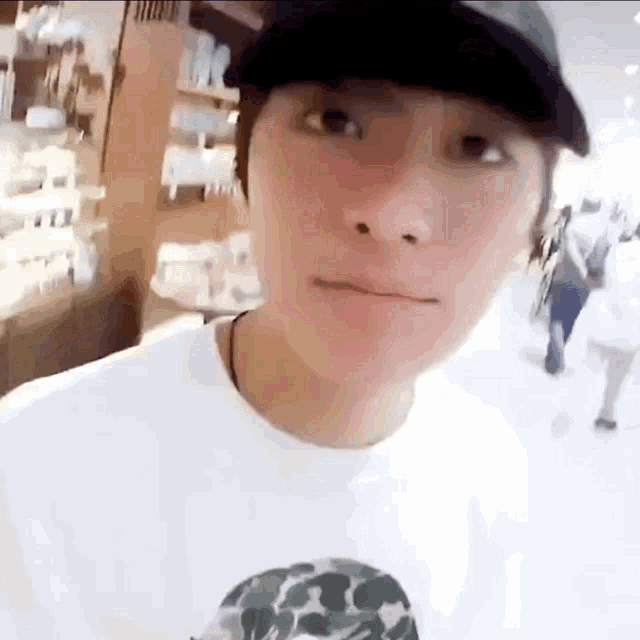 a young man wearing a hat and a white t-shirt is making a funny face .