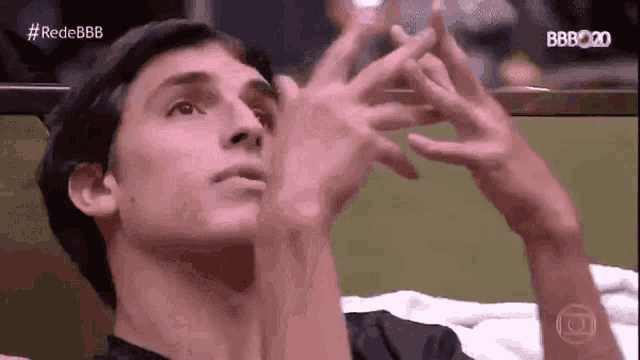 a young man is sitting on a bed with his hands in his face .