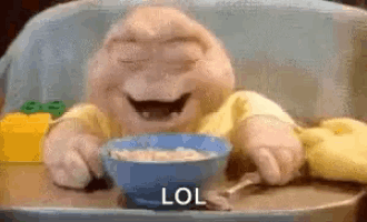 a baby is sitting in a high chair eating cereal from a bowl .