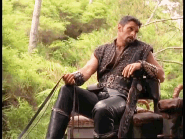 a man is sitting on a chair holding a whip