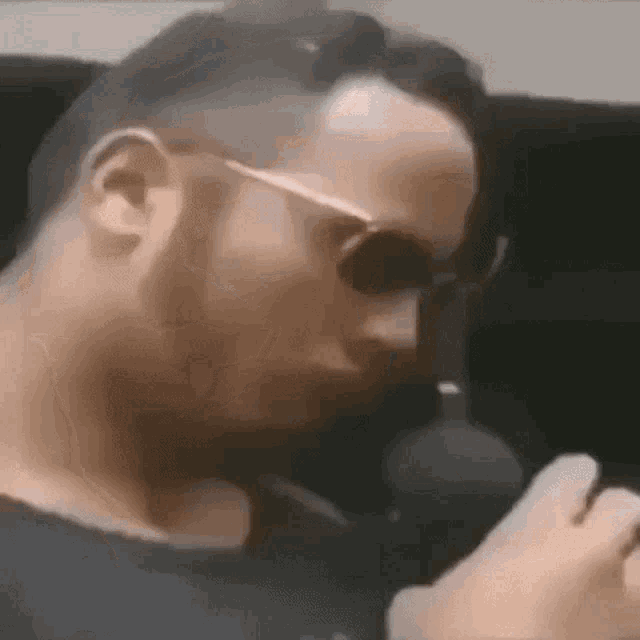 a close up of a man wearing sunglasses talking on a phone .