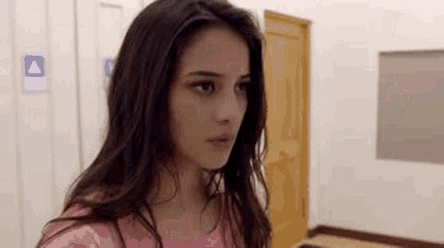 a woman is standing in a hallway looking at the camera .