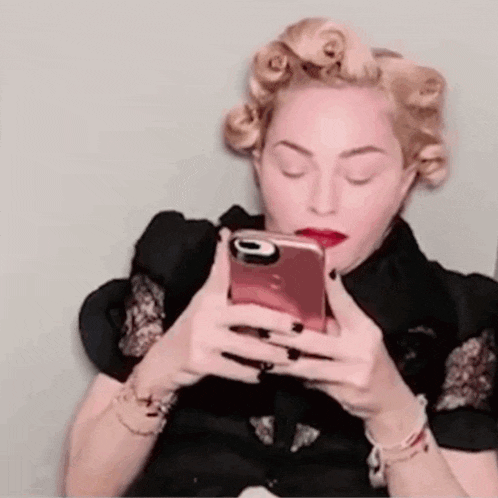 a woman with curlers in her hair is holding a cell phone .