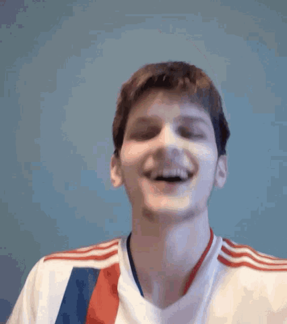a man wearing a white shirt with red and blue stripes is smiling