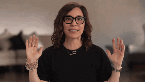 a woman wearing glasses and a black shirt has a necklace on her neck that says i am enough