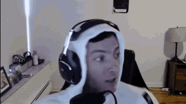 a man wearing headphones and a hooded jacket is sitting in a chair .