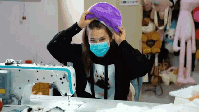 a woman wearing a mask is using a sewing machine to make a hat