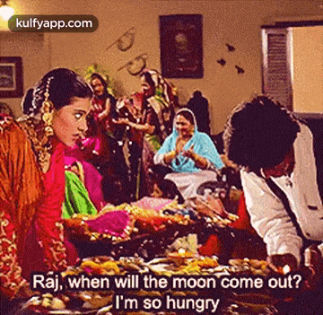 a group of people are gathered around a table with food and a man is talking to a woman .