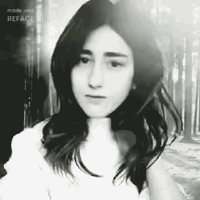 a black and white photo of a woman with trees in the background .