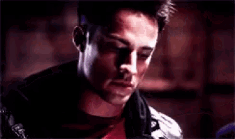 a close up of a man 's face with a red shirt and a black jacket