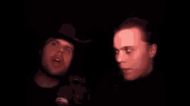 two men are talking to each other in a dark room .