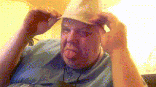 a man wearing a cowboy hat and glasses looks at the camera