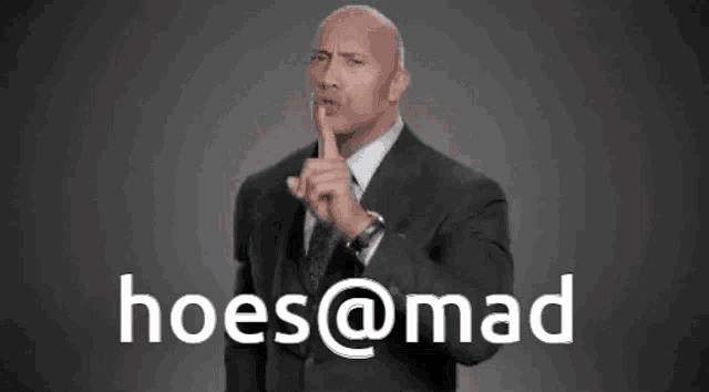 a man in a suit holds his finger to his lips and says hoes@mad