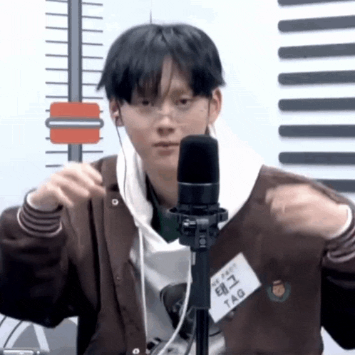 a young man is wearing headphones and a name tag while standing in front of a microphone .