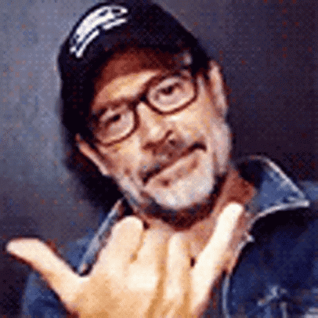 a man wearing glasses and a hat is making a hand gesture