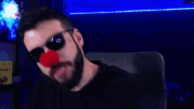 a man with a beard wearing sunglasses is making a funny face in front of a blue background .