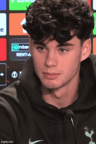 a young man with curly hair wearing a black nike sweatshirt