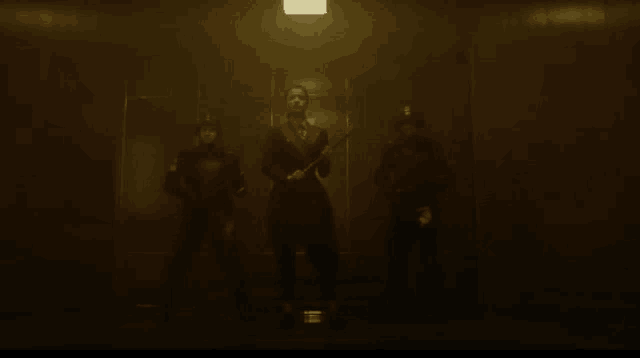 a group of people standing in a dark room holding weapons .