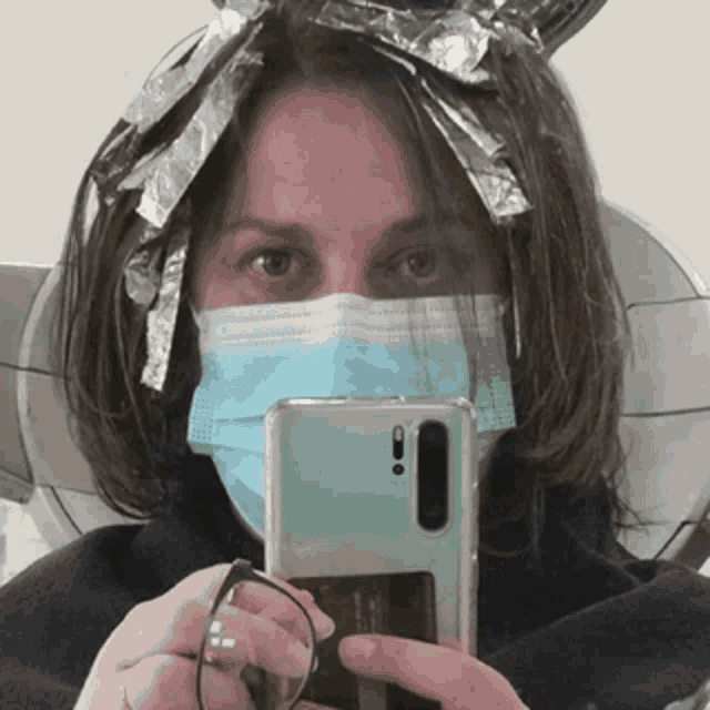 a woman wearing a mask is taking a picture of herself