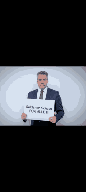 a man in a suit and tie is holding up a sign that says goldener schuss for alle iii