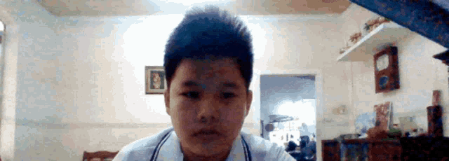 a boy in a white shirt is looking at the camera