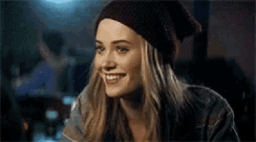 the woman is wearing a beanie and smiling .